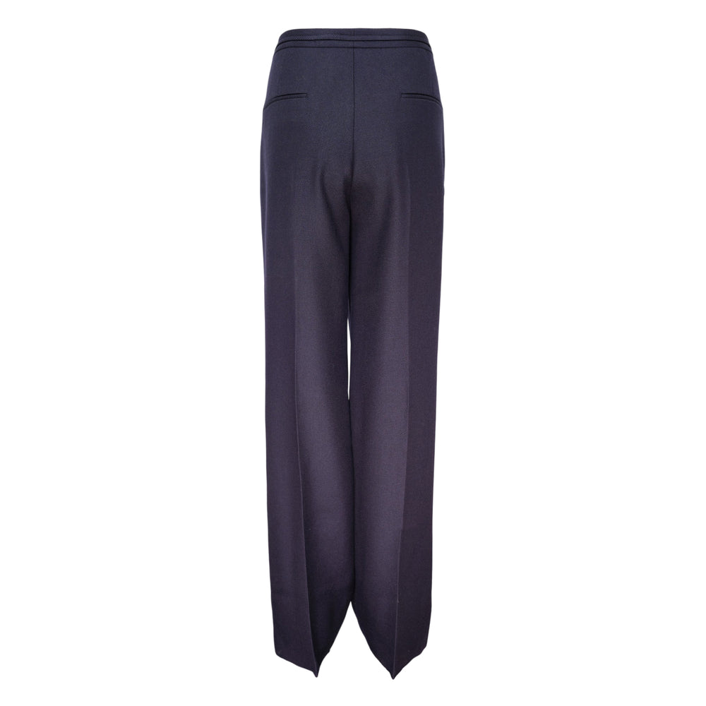 Jil Sander wide-leg tailored pants in navy with high-rise waist, D-ring belt hardware, pressed front crease, and contrast stripe trim at the hem