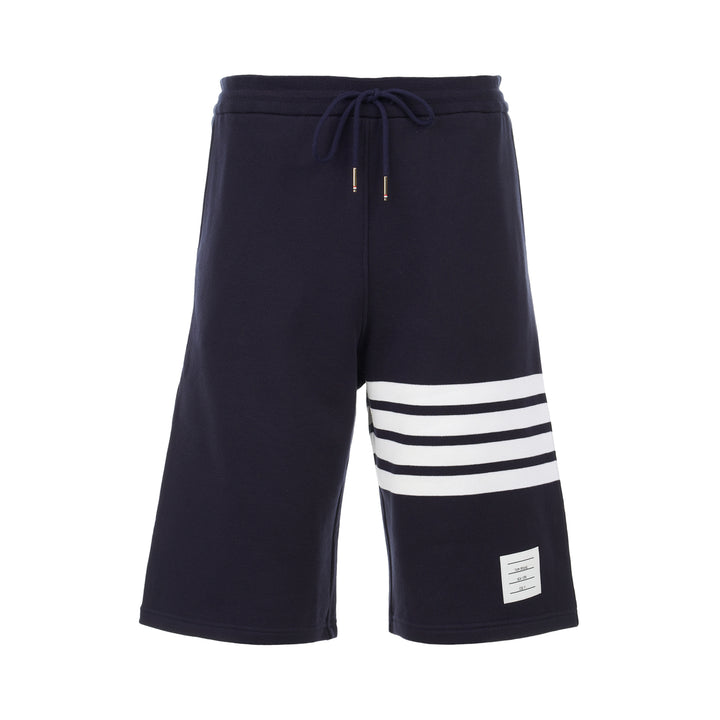 Thom Browne navy cotton sweat shorts with drawstring waist, white 4-Bar stripe on one leg and woven label patch at the hem