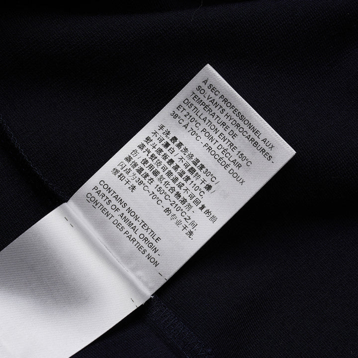 Thom Browne navy short sleeve polo with tonal 4-bar stripe on the sleeve, button placket, and woven brand label at the hem