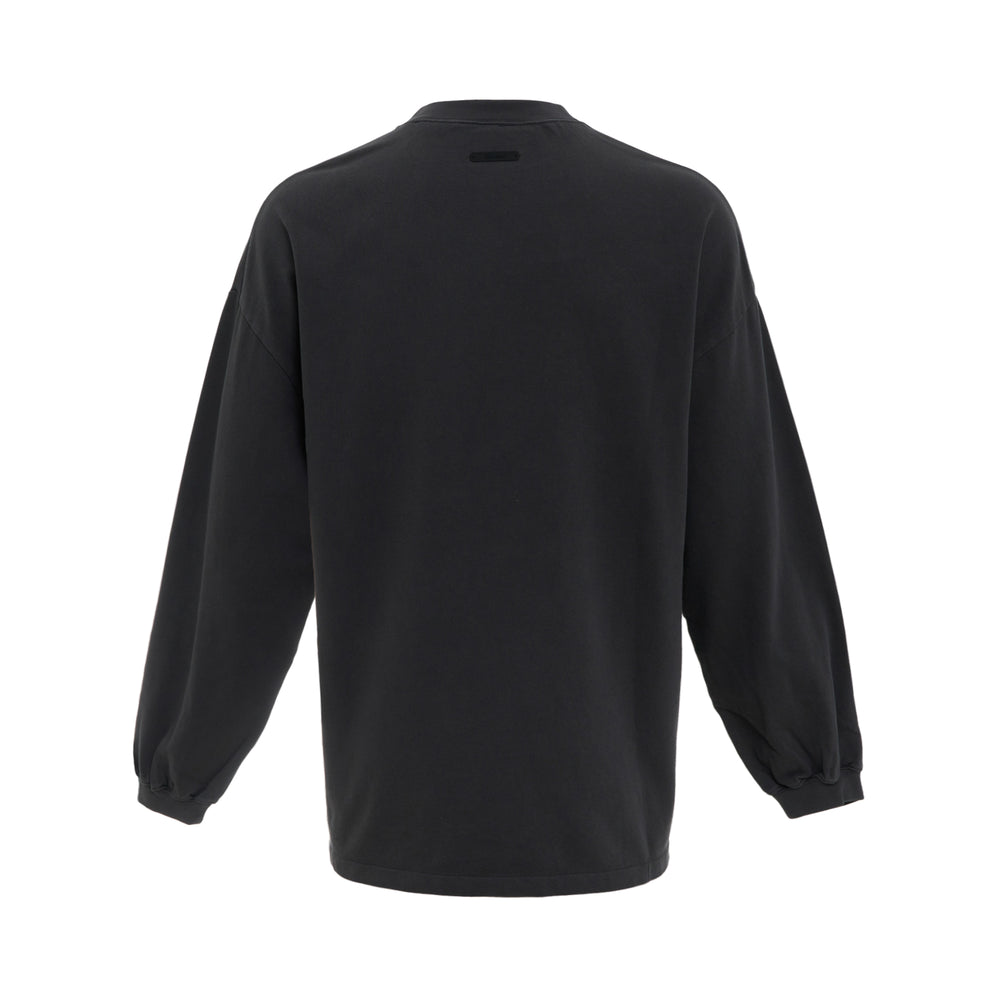 Fear of God Essentials Campus 90s Long Sleeve Tee in black with oversized arch collegiate logo graphic in sage, relaxed drop-shoulder fit