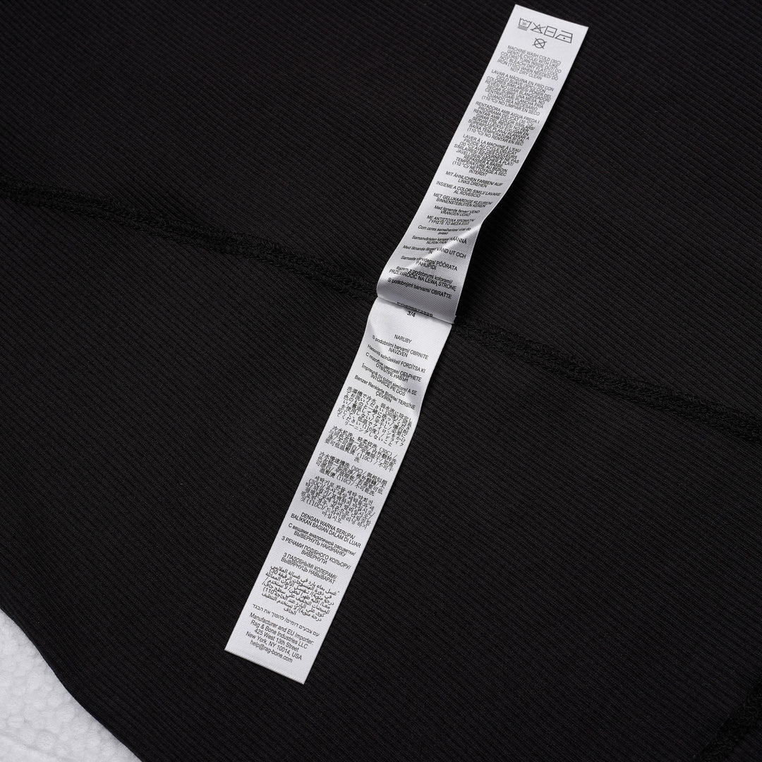 rag & bone Essential Rib Muscle Tank in black, featuring a high racer neckline, fine ribbed knit fabric, and a form-fitting sleeveless silhouette, shown on a flat lay against a white background