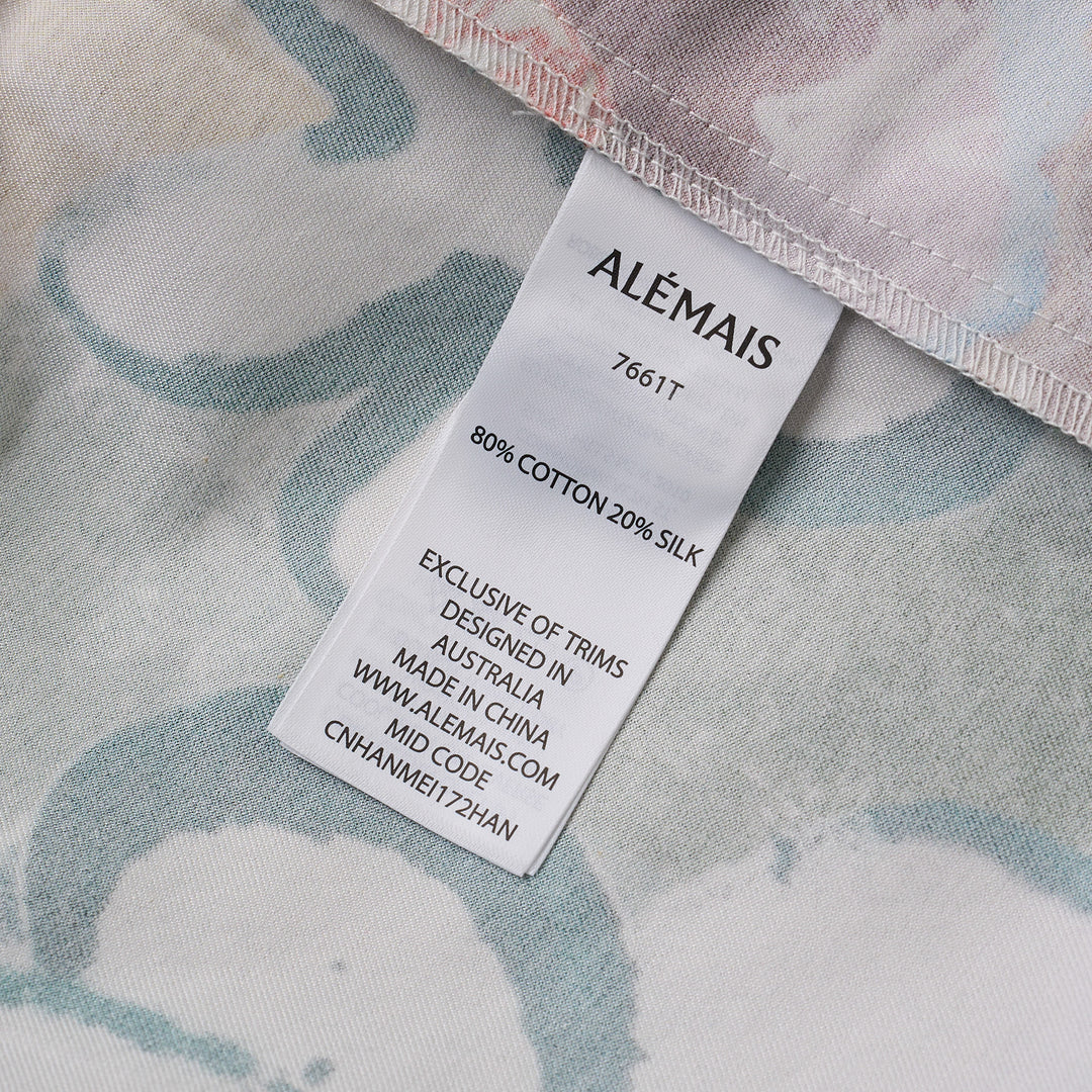 Alemais Tangible Love short-sleeve shirt with patchwork hand-painted panels featuring crocodile, floral, and abstract motifs, oversized hem pockets, and contrast stripe trim on a white background