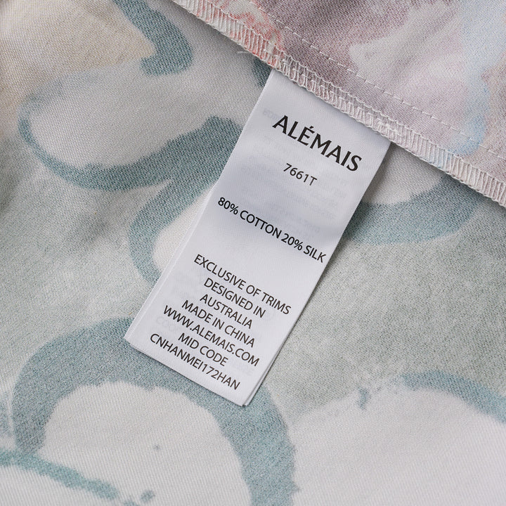 Alemais Tangible Love short-sleeve shirt with patchwork hand-painted panels featuring crocodile, floral, and abstract motifs, oversized hem pockets, and contrast stripe trim on a white background