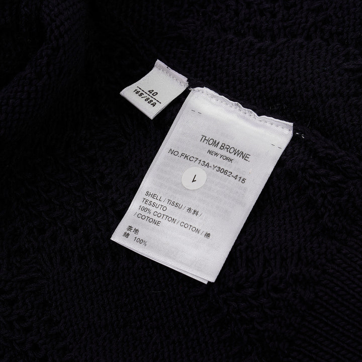 Thom Browne navy pointelle-knit short sleeve V-neck cardigan with contrast ivory trim, four-bar stripe on the sleeve, and mother-of-pearl button fastening