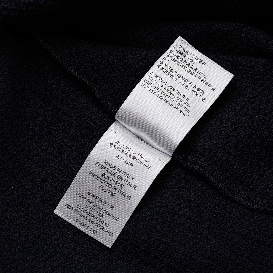 Thom Browne navy textured knit relaxed fit short sleeve polo with spread collar, five-button placket, chest pocket, and signature branding tab at the hem