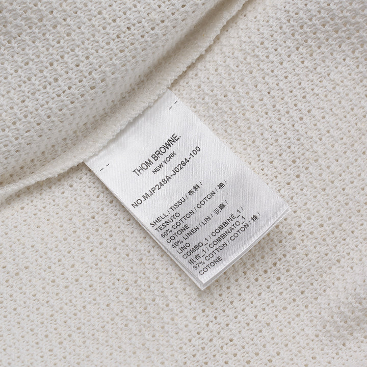 Thom Browne navy textured knit relaxed fit short sleeve polo with spread collar, five-button placket, chest pocket, and signature branding tab at the hem
