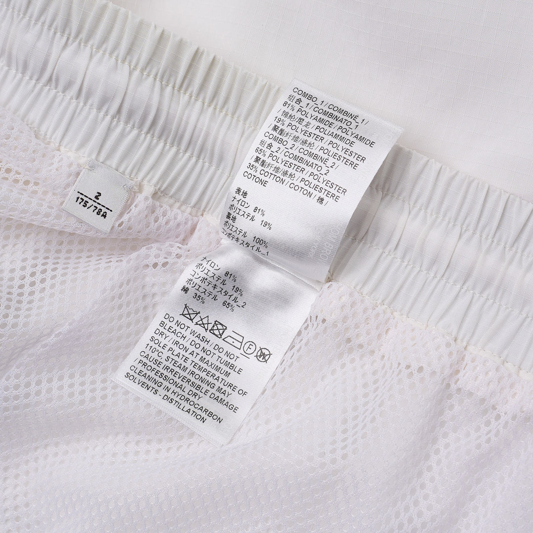 Thom Browne white drawcord waist track shorts with signature 4-bar navy stripe across the hem and elasticated waistband