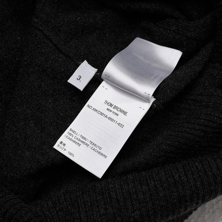 Thom Browne Classic V-Neck Cardigan in dark charcoal grey with signature four-bar white and black stripe on the sleeve, button-front closure, and ribbed hem