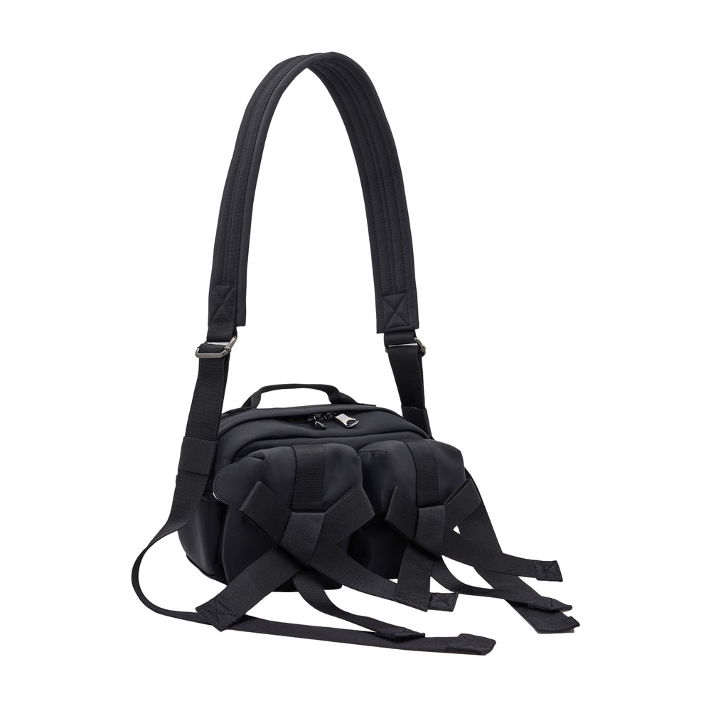 Simone Rocha Classic Bow Crossbody Bag in black, showing sculptural woven bow detailing on the front, dual zip closure, top carry handle, and adjustable padded shoulder strap