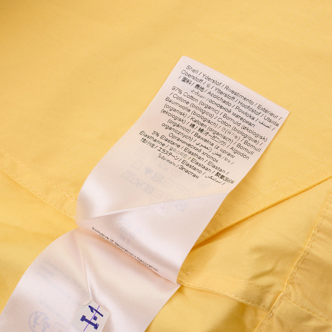 Ganni yellow stretch cotton smocked mini dress with puff sleeves and drop-waist bubble skirt, shot against a white background