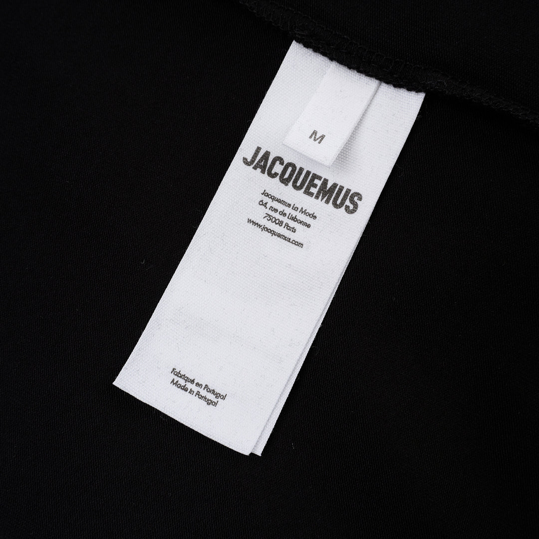 Jacquemus Gros Grain Long Sleeve Tee in black — cropped mock-neck jersey top with tonal grosgrain logo label at the chest, photographed flat on a white background