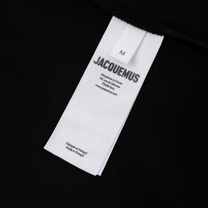 Jacquemus Gros Grain Long Sleeve Tee in black — cropped mock-neck jersey top with tonal grosgrain logo label at the chest, photographed flat on a white background