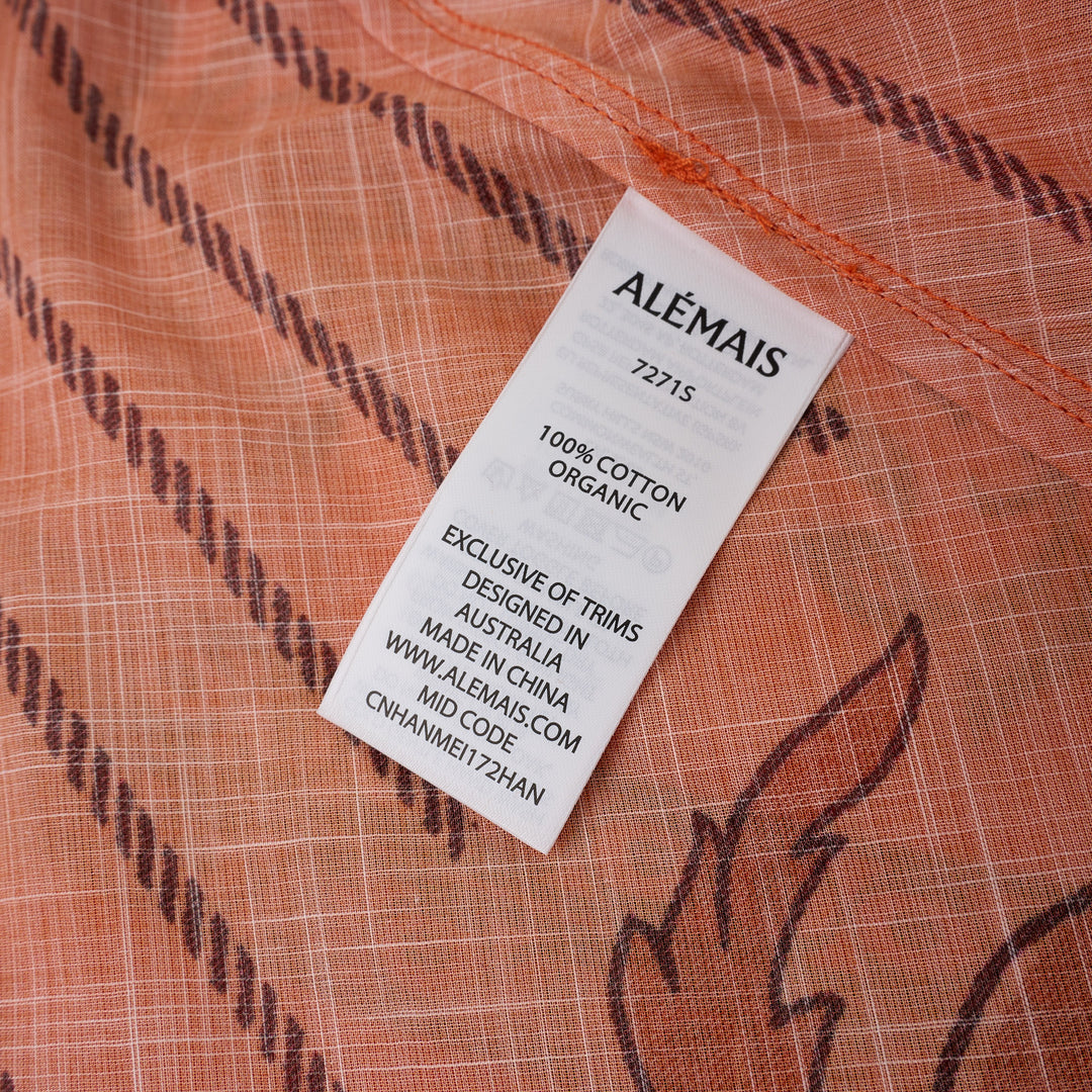 Alemais Boathouse Midi Skirt in orange with tropical beach print featuring palm trees, sun illustration, and floral border hem, displayed on white background