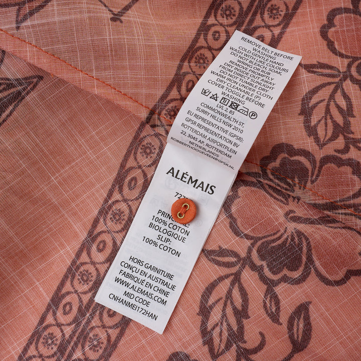 Alemais Boathouse Mini Dress in orange cotton with tropical palm and floral border print, balloon sleeves, gathered neckline with tassel tie, and coordinating rope belt