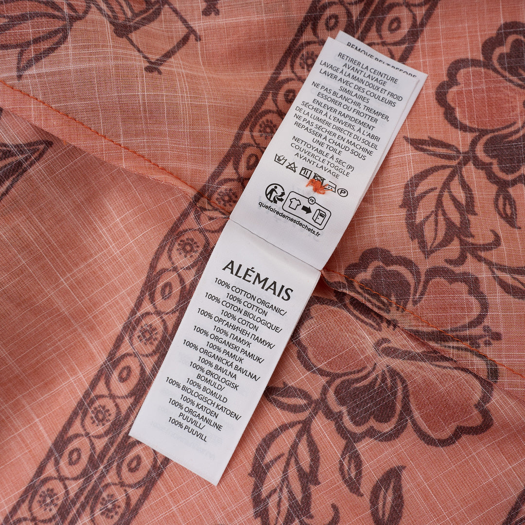 Alemais Boathouse Mini Dress in orange cotton with tropical palm and floral border print, balloon sleeves, gathered neckline with tassel tie, and coordinating rope belt