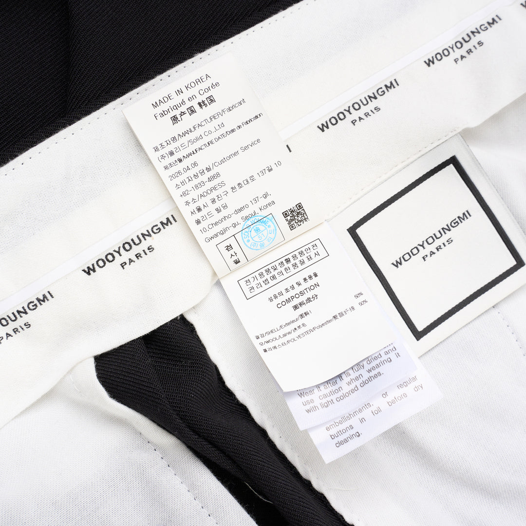 Wooyoungmi black pleated high-rise trousers with double front pleats and side metal buckle adjuster, displayed flat on white background - view 4