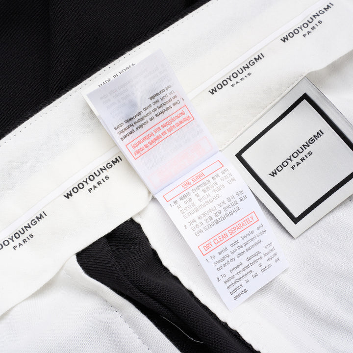Wooyoungmi black pleated high-rise trousers with double front pleats and side metal buckle adjuster, displayed flat on white background - view 7