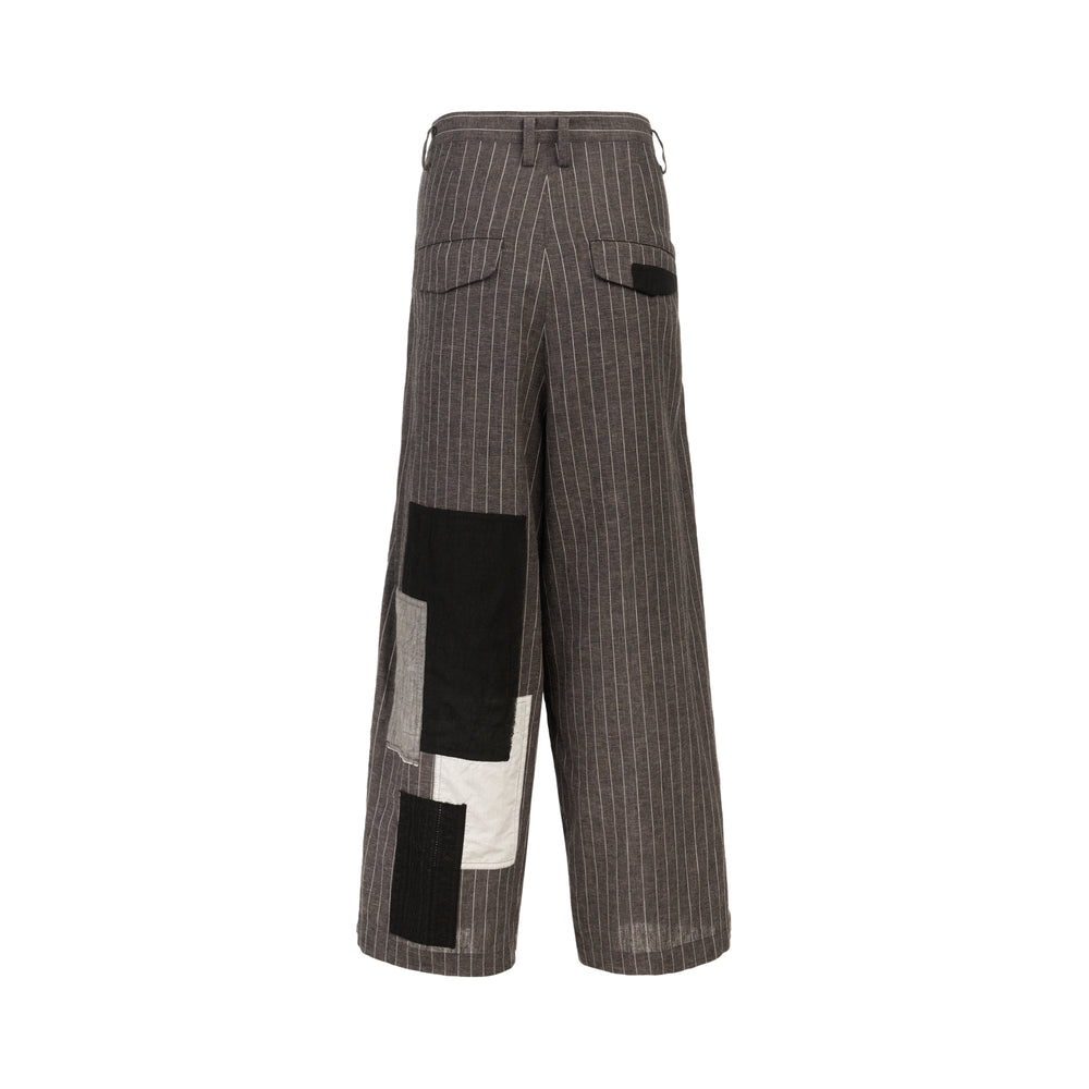 Y's grey pinstripe wide-leg trousers with raw-edged black and ecru patchwork appliqués, deep front tucks, and a single button waistband closure - view 2