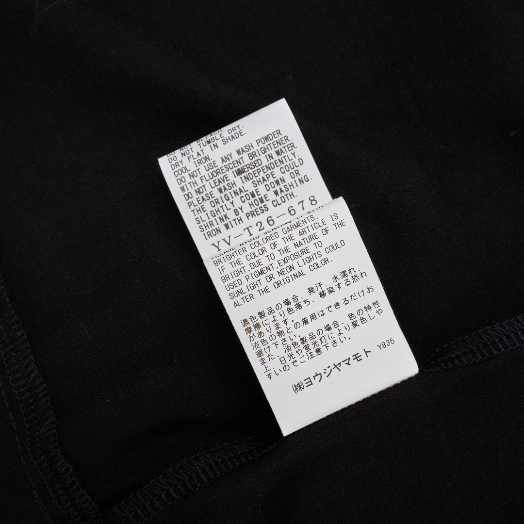 Y's black oversized round neck shirt dress with short folded cuffs, layered T-shirt upper, and buttoned skirt panel, displayed on white background - view 6