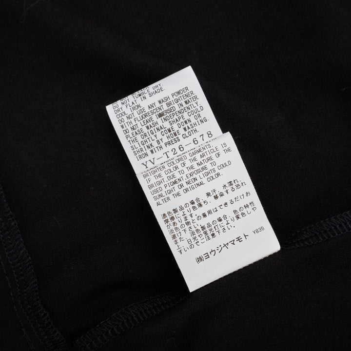Y's black oversized round neck shirt dress with short folded cuffs, layered T-shirt upper, and buttoned skirt panel, displayed on white background - view 6