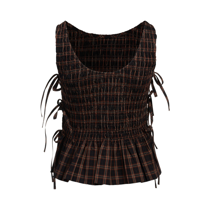 Ganni Check Smocked Tie Blouse in dark yarn-dyed plaid with all-over shirring, adjustable side tie bows, and a pleated peplum hem, shown flat on a white background