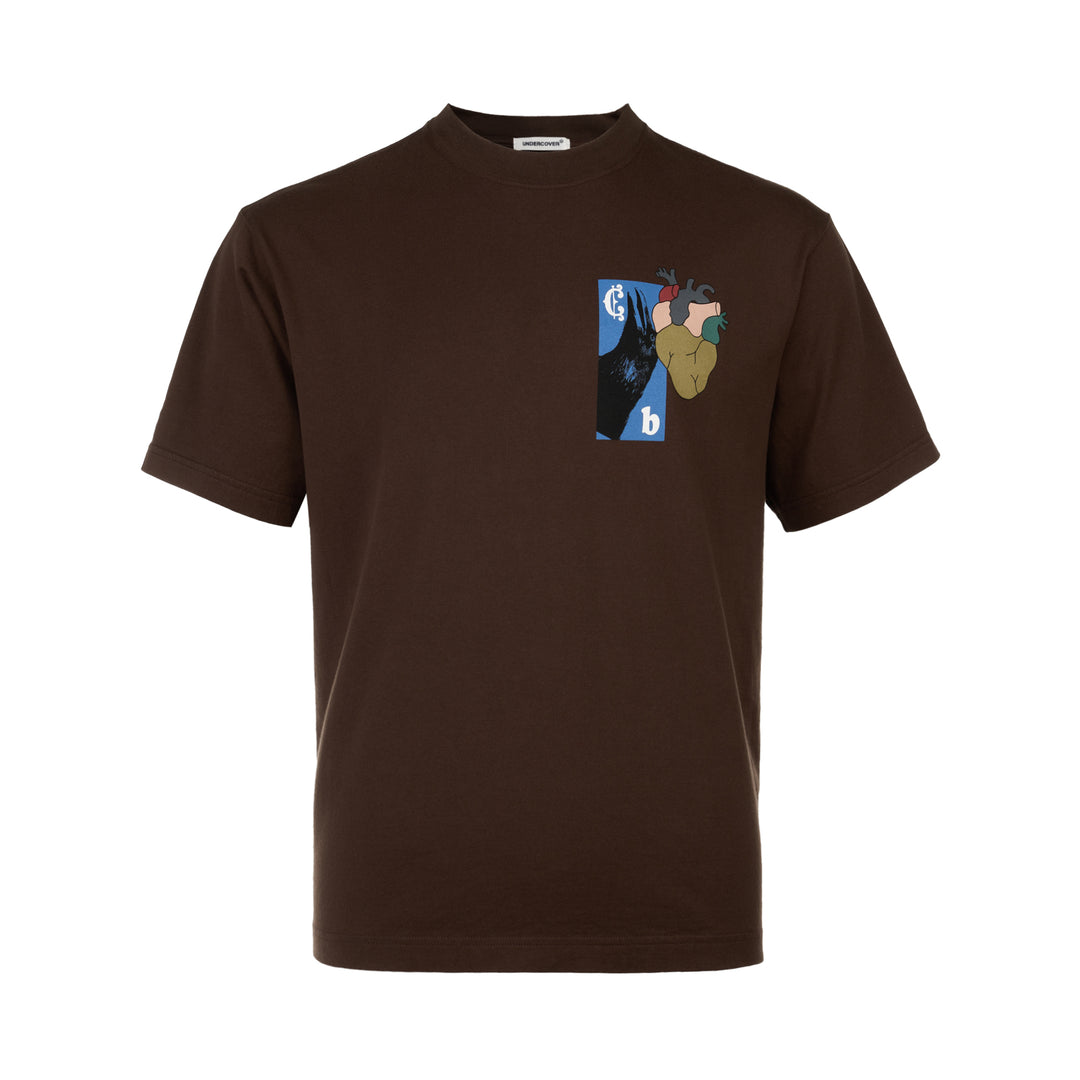 Undercover Heart Graphic Tee in dark brown, featuring a collage-style chest graphic with an anatomical heart, raven motif, and Old English typography on a relaxed-fit crew neck cotton tee.