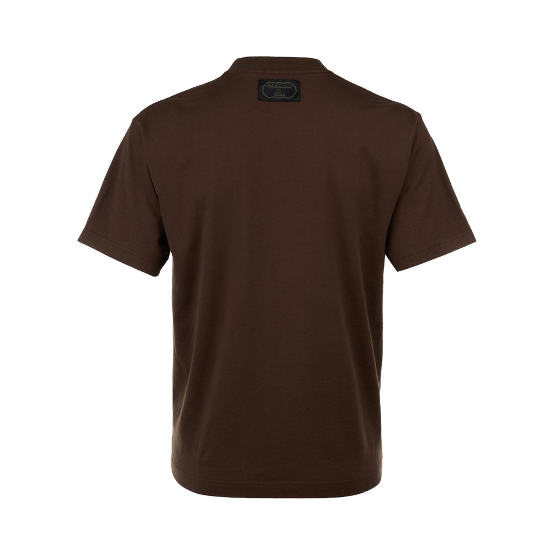 Undercover Heart Graphic Tee in dark brown, featuring a collage-style chest graphic with an anatomical heart, raven motif, and Old English typography on a relaxed-fit crew neck cotton tee.