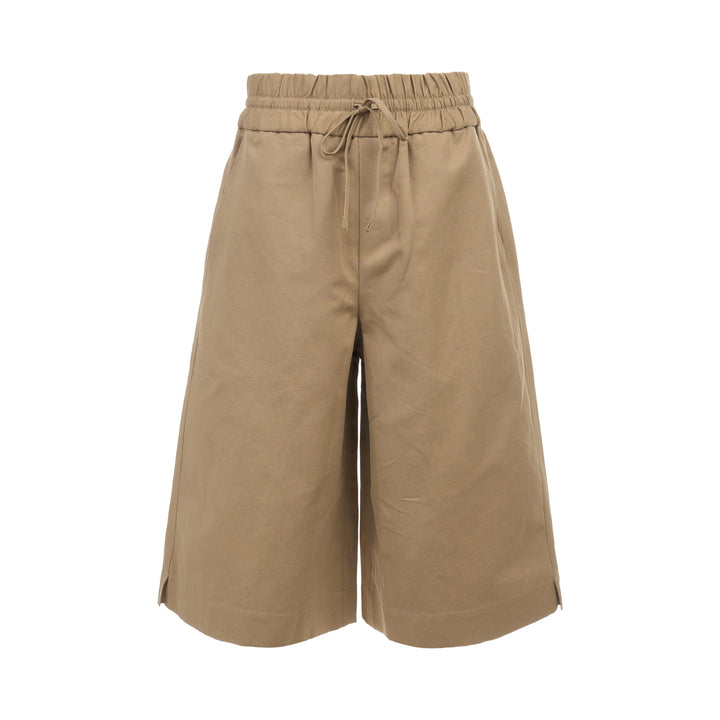 AMI Elasticated Large Bermuda Shorts in khaki tan, featuring a wide-leg silhouette, elasticated paper-bag waistband with drawstring, and hem side slits, displayed flat on a white background
