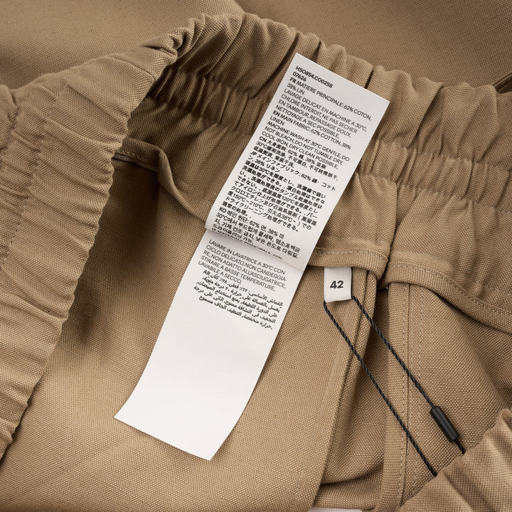 AMI Elasticated Large Bermuda Shorts in khaki tan, featuring a wide-leg silhouette, elasticated paper-bag waistband with drawstring, and hem side slits, displayed flat on a white background - view 4