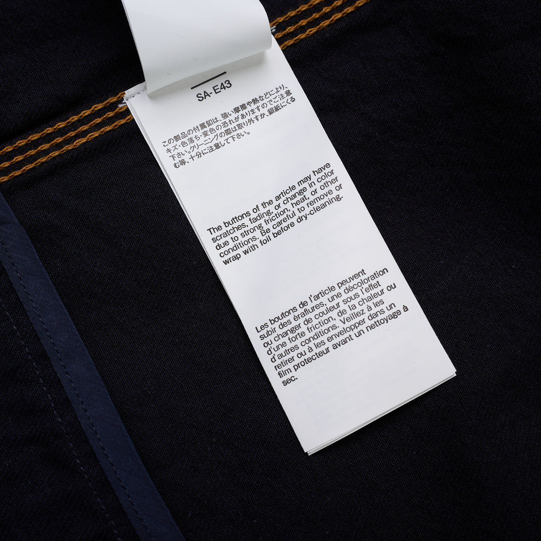 sacai indigo denim trucker jacket with contrast topstitching, pleated front panels, button-flap chest pockets and a layered hem, shown from the front - view 4