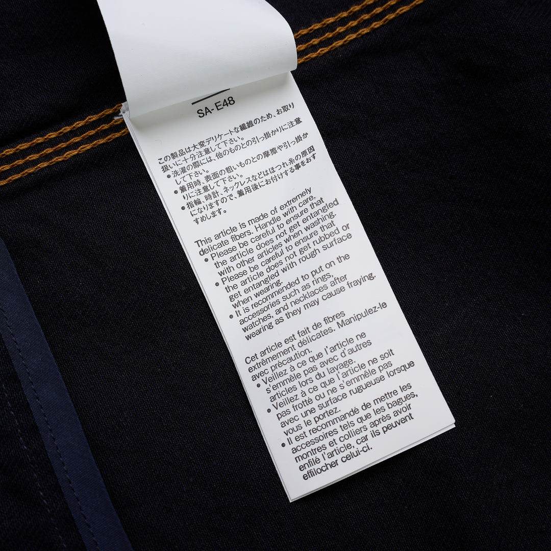 sacai indigo denim trucker jacket with contrast topstitching, pleated front panels, button-flap chest pockets and a layered hem, shown from the front - view 5