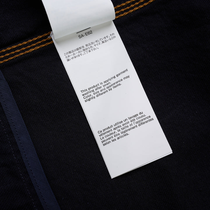 sacai indigo denim trucker jacket with contrast topstitching, pleated front panels, button-flap chest pockets and a layered hem, shown from the front - view 6