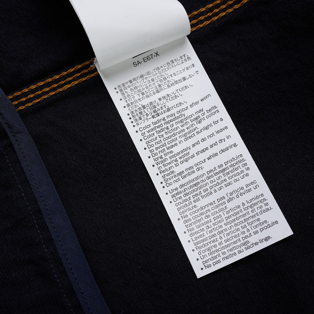 sacai indigo denim trucker jacket with contrast topstitching, pleated front panels, button-flap chest pockets and a layered hem, shown from the front - view 7