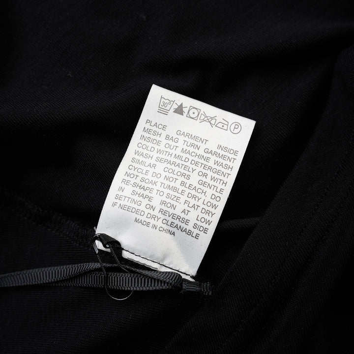 Black short-sleeve crew neck jersey tee with gathered side draping and an asymmetric hem, shown flat against a white background - view 3
