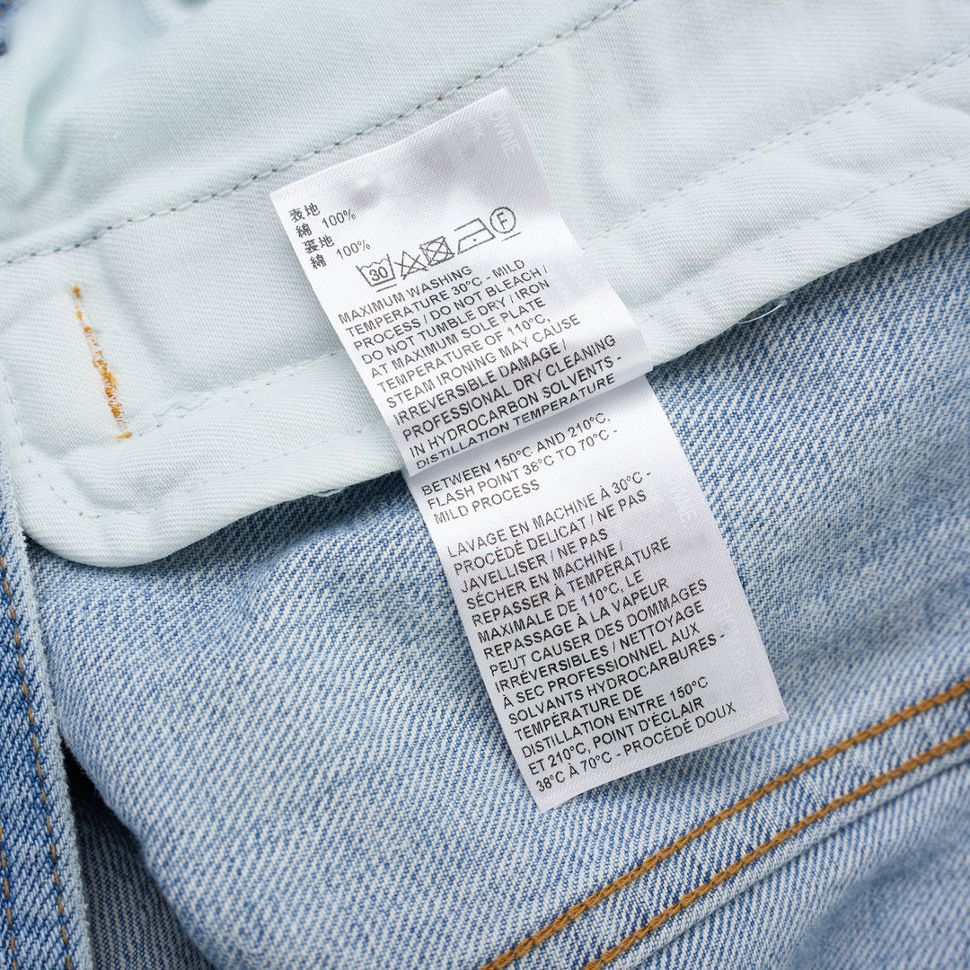 Thom Browne Backstrap Utility Jacket in light-wash denim with twin chest flap pockets and brass buttons, shown from the front - view 4