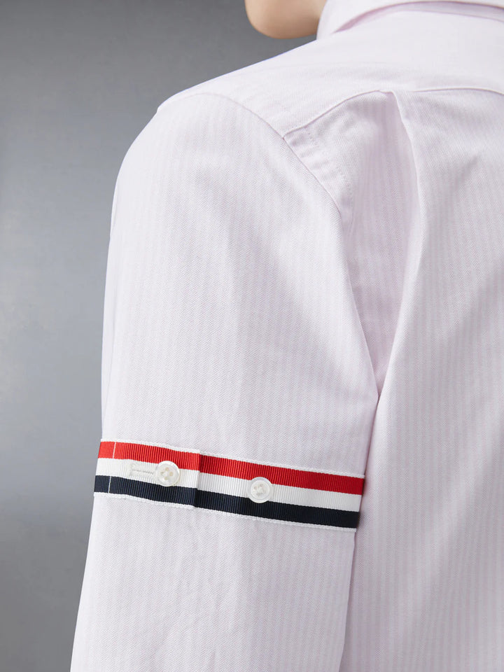Thom Browne classic long sleeve light blue pinstripe shirt with tricolor grosgrain ribbon armbands, front view on white background