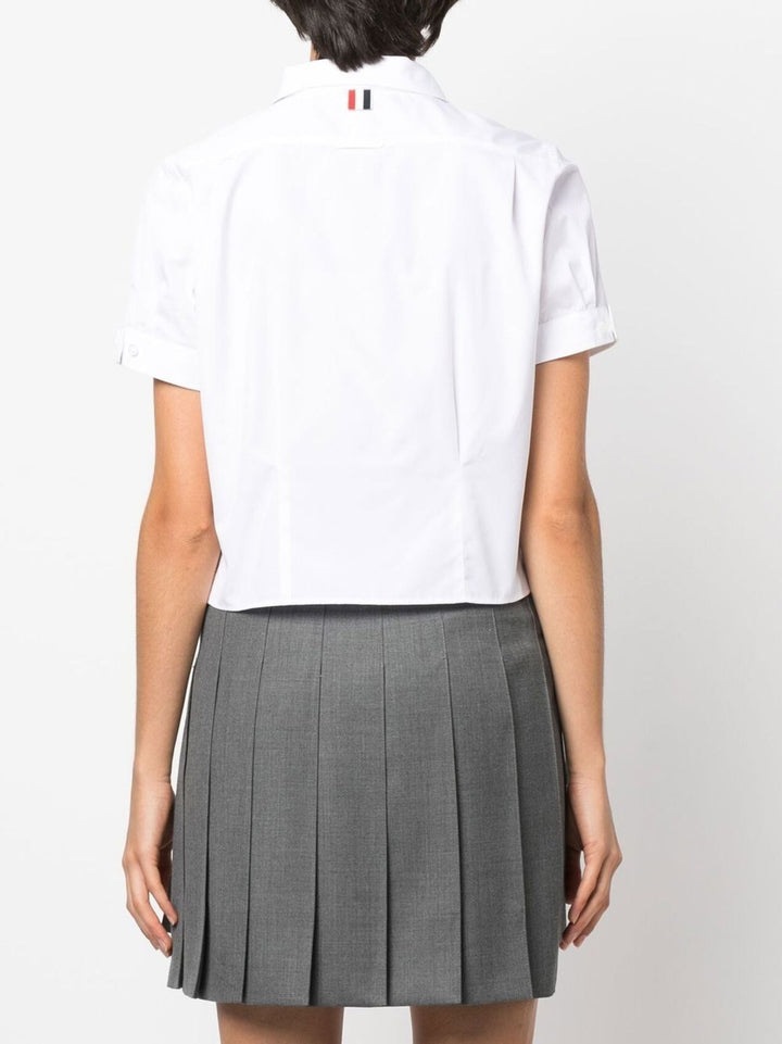 Thom Browne white cropped short sleeve button-front shirt with point collar and cuffed sleeves on a plain white background