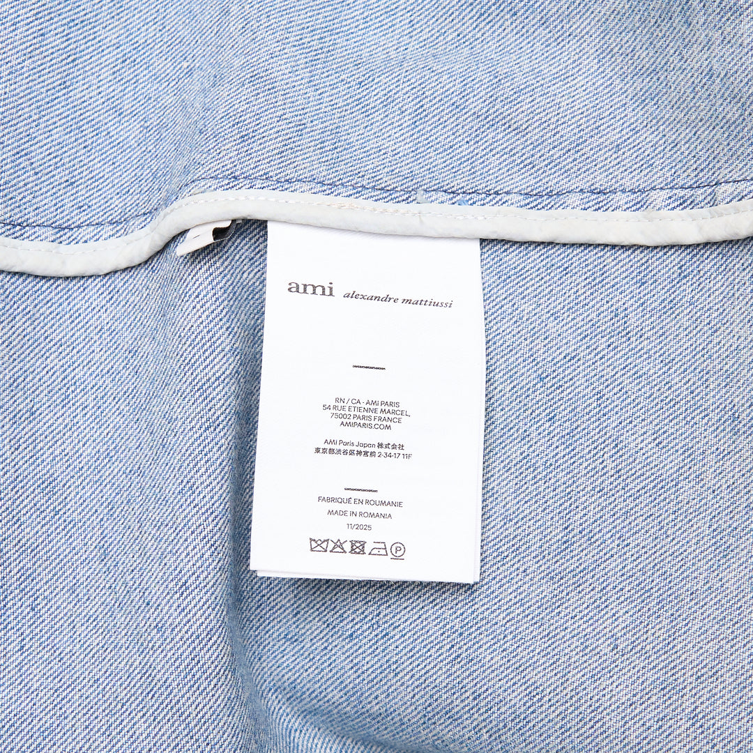 AMI Paris Ami de Cœur Zipped Blouson in washed blue denim with full-length zip closure, pointed collar, chest patch pocket with heart logo, and cropped silhouette