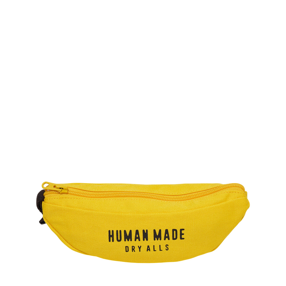 Human Made Banana Zip Pouch in yellow canvas, shaped like a banana with a zip closure, dark stem detail, and a red heart logo patch