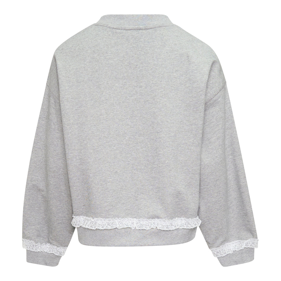 Ganni Isoli Sweater in heather grey marl with white lace frill trim at the hem and cuffs, and an embroidered heart-shaped Ganni logo patch on the chest