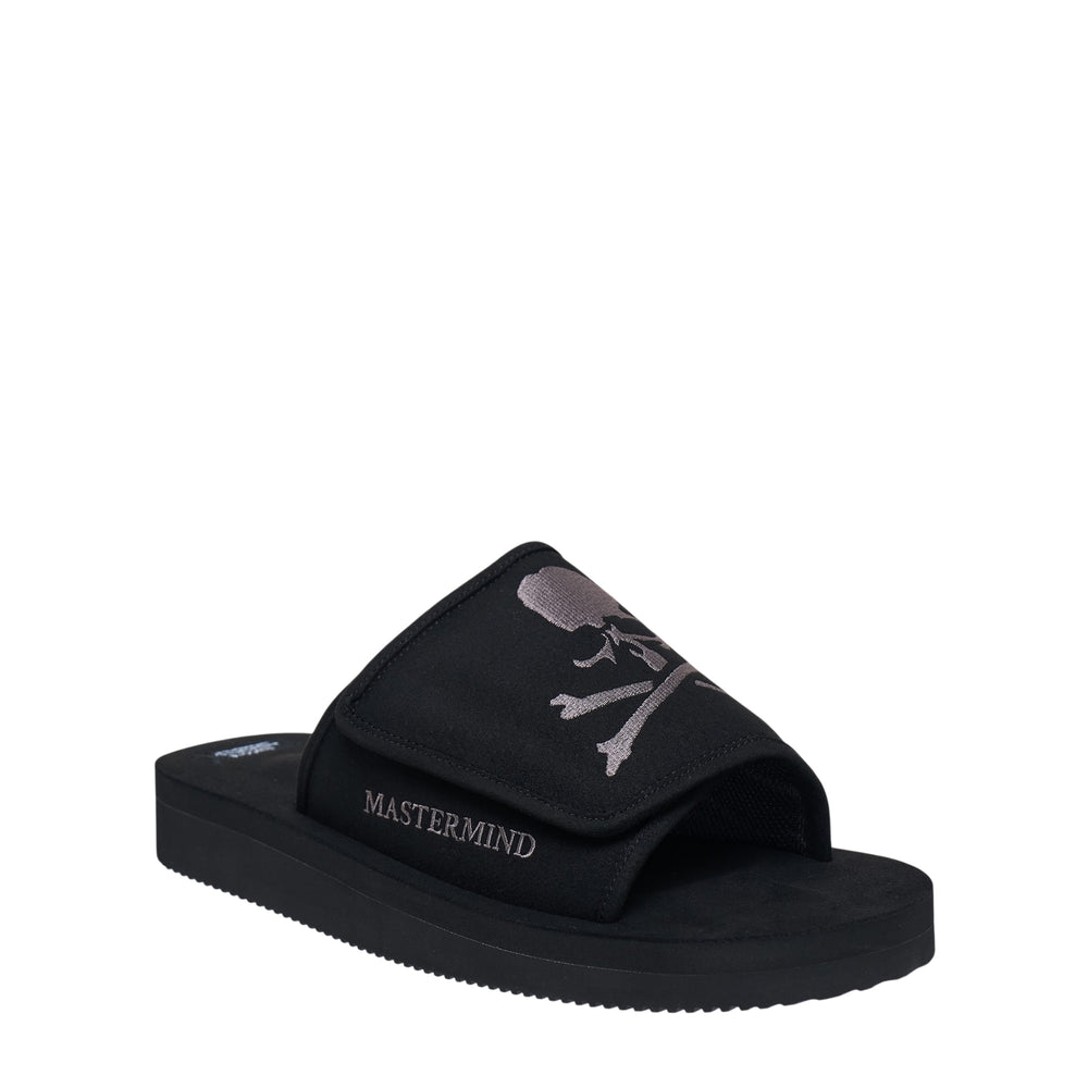 Suicoke x Mastermind taupe suede flat slide sandal with padded Velcro strap featuring tone-on-tone skull graphic and Mastermind embroidered lettering, set on a ridged rubber sole