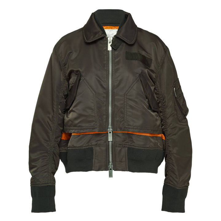 sacai Nylon Twill Bomber Blouson in olive green, featuring dual zip closure, contrast amber yellow hem lining, angled chest pockets, and ribbed knit trims, displayed flat on a white background