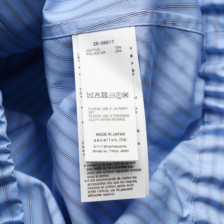 sacai black poplin zip-up jacket with layered sleeve detailing, silver zipper, spread collar with snap tabs, and ribbed hem, front view on white background