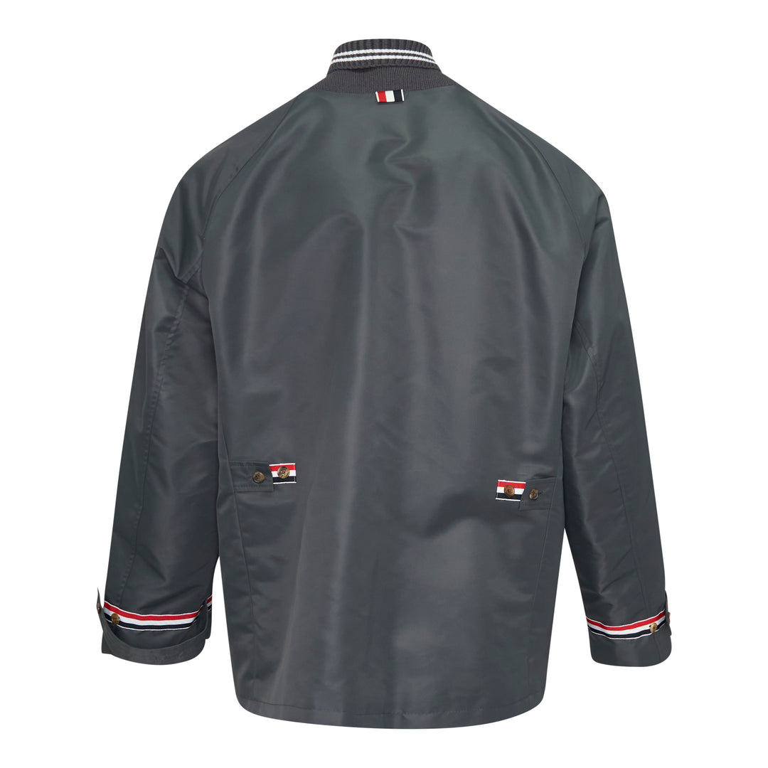 Back view of Thom Browne Cropped Field Jacket in slate grey with ribbed collar, signature red, white, and blue grosgrain trim at collar label, rear pocket tabs, and cuffs