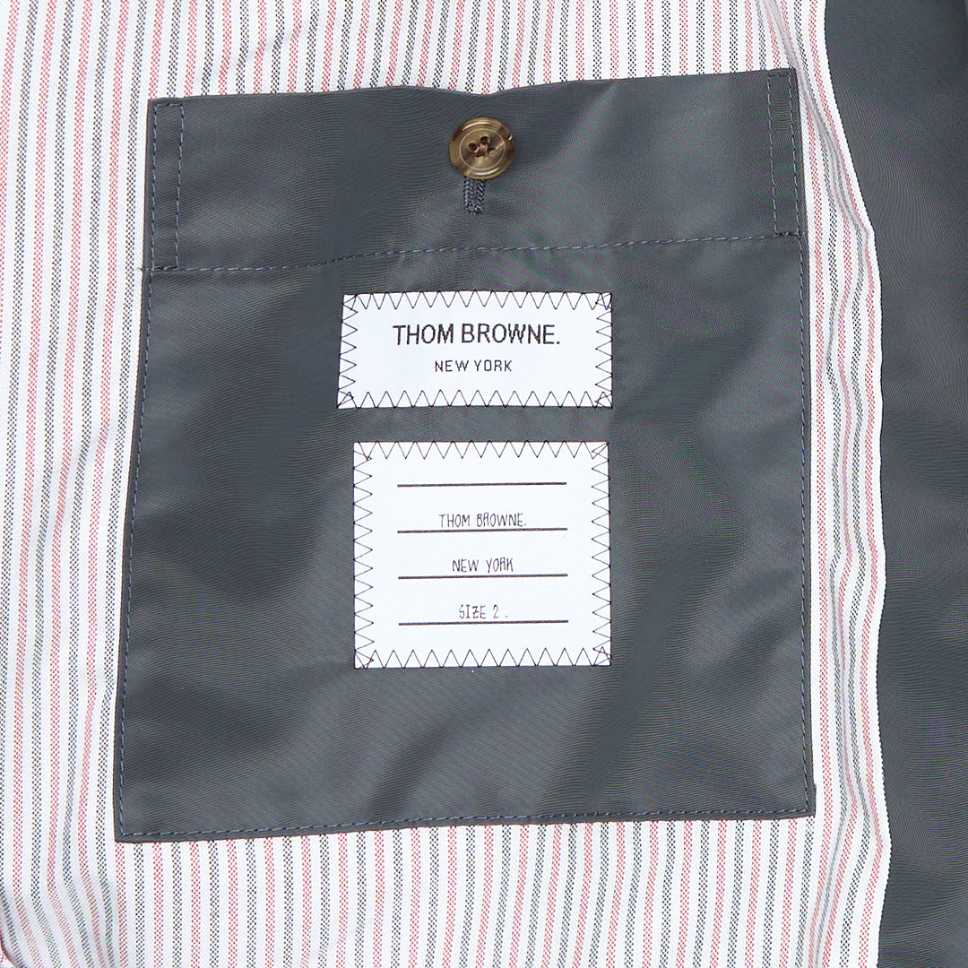 Back view of Thom Browne Cropped Field Jacket in slate grey with ribbed collar, signature red, white, and blue grosgrain trim at collar label, rear pocket tabs, and cuffs