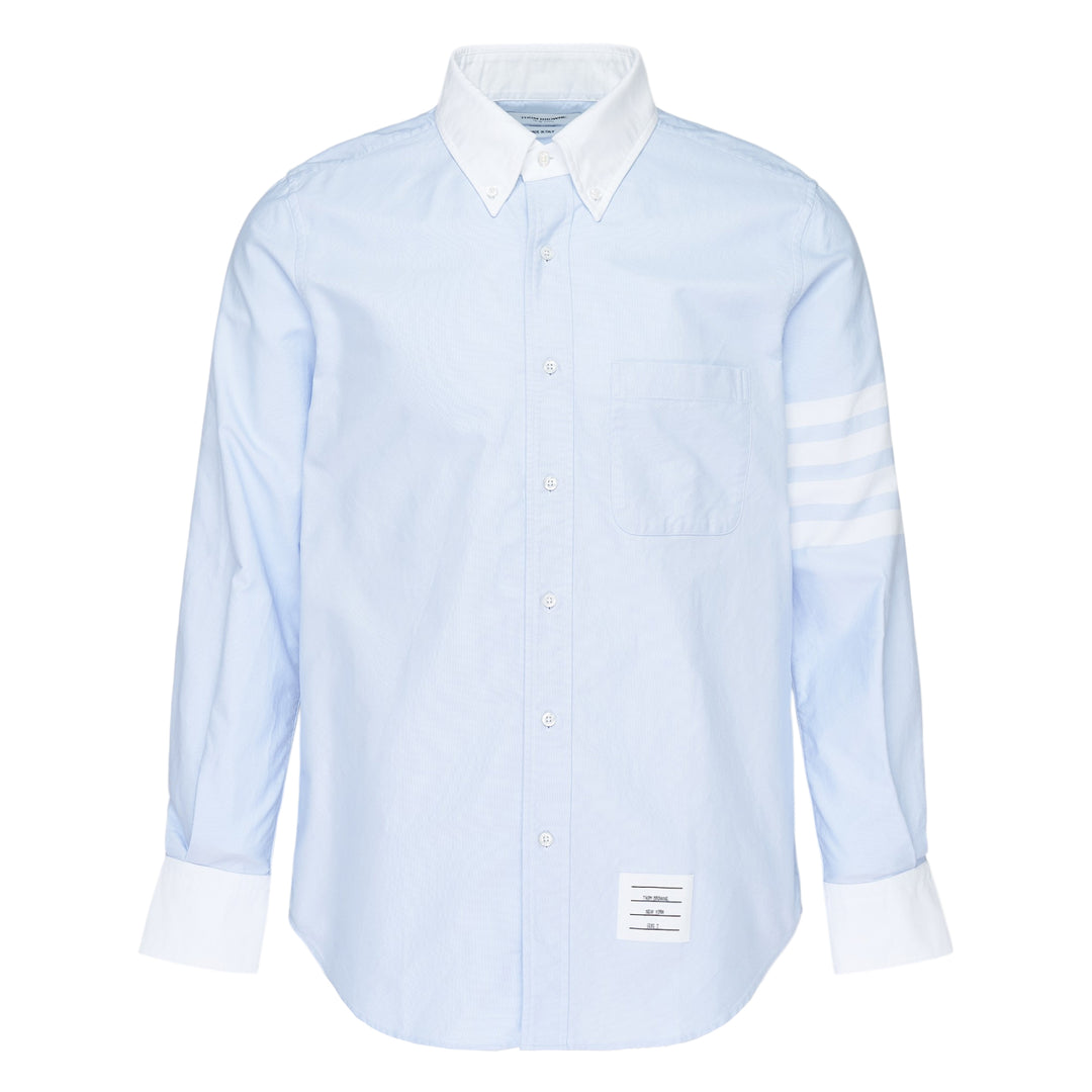 Thom Browne straight fit light blue Oxford long sleeve shirt with contrast white button-down collar, double cuffs, four-bar stripe on sleeve, and chest patch pocket