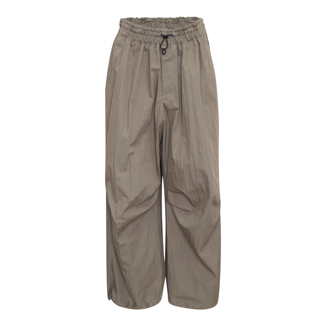 Yohji Yamamoto wide leg parachute pants in taupe with elasticated ruched waistband, drawstring toggle closure, and voluminous crinkled shell fabric