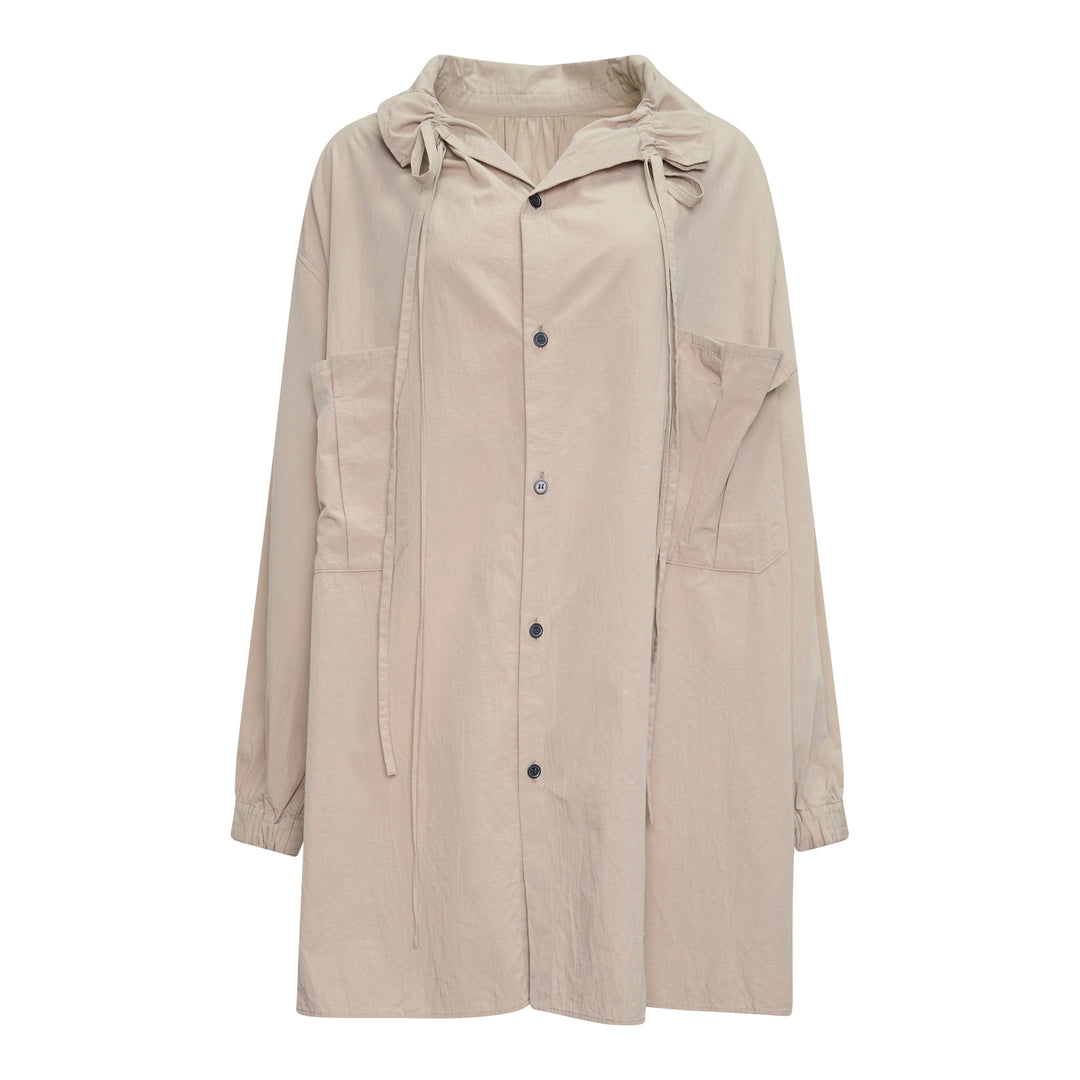 Y's Gather Collar Hooded Coat in sand beige, featuring a drawstring gathered hood with bow-tie fastenings, button-front closure, large hip patch pockets, and elasticated cuffs, displayed flat on a white background