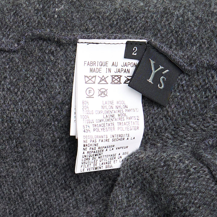 Y's Appliqué Short Cardigan in grey marl wool-blend, featuring cascading black mixed-fabric appliqué panels in organza and boucle across the front, with button fastening and ribbed cuffs, back view on white background
