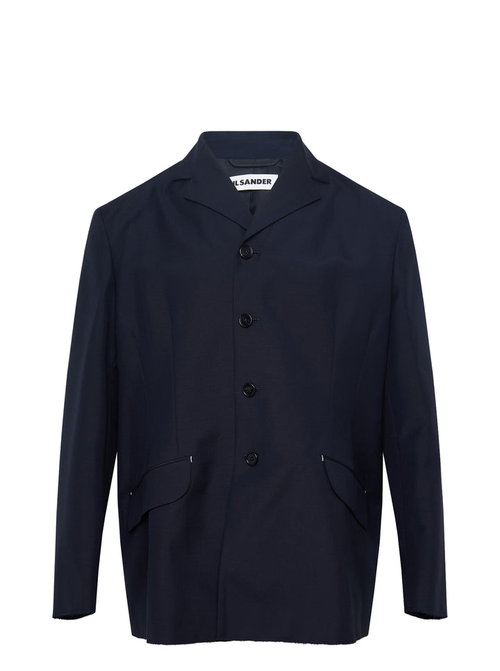Jil Sander navy fil-a-fil wool jacket with camp collar, four-button fastening, and curved flap pockets with metal hardware — front view on white background